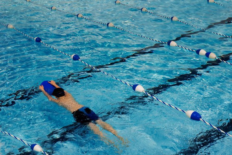 una persona nadando en una piscina mientras se agarra a una flotadora